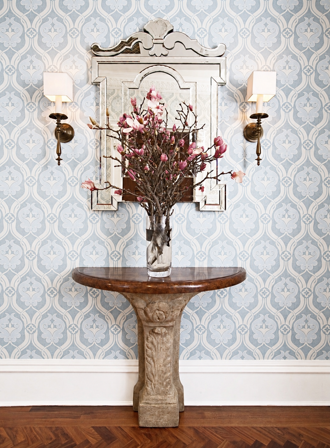 Elegant entryway with blue damask wallpaper, Venetian mirror, and magnolia branches