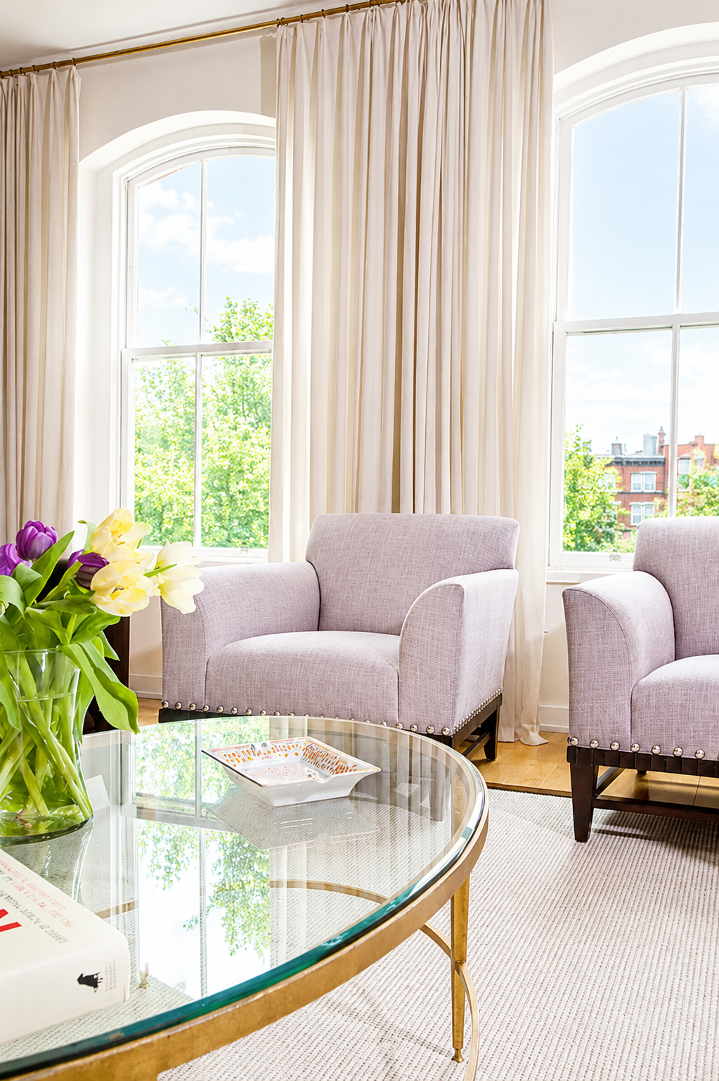 Sitting room with arched windows, lavender armchairs, and gold coffee table