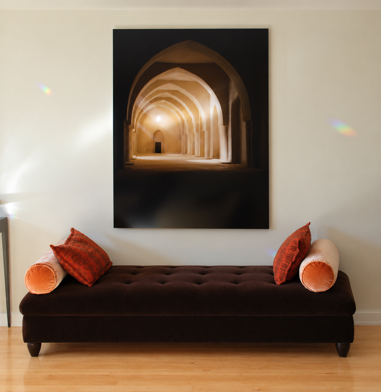 Tufted chocolate bench with coral bolster pillows beneath a large architectural photograph