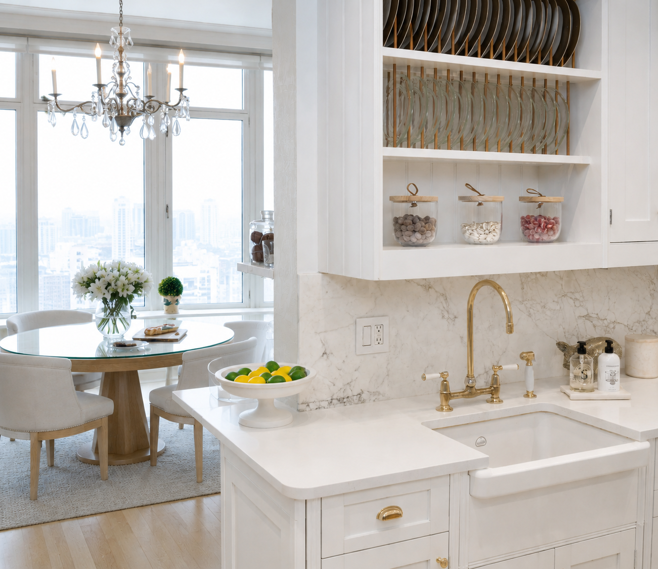 White kitchen with brass fixtures, marble backsplash, and adjacent dining nook with crystal chandelier